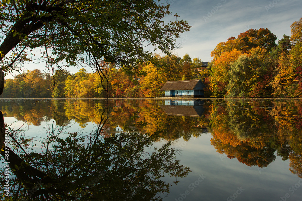 Landscape with beautiful house on a lake with colourful leafs in autumn season