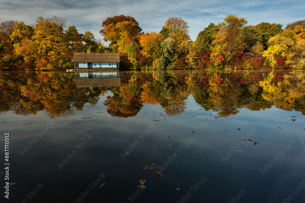 Landscape with beautiful house on a lake with colourful leafs in autumn season