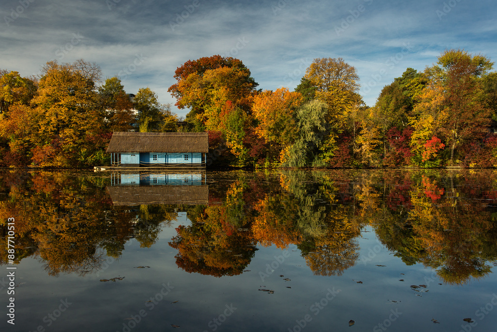 Landscape with beautiful house on a lake with colourful leafs in autumn season