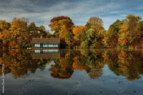 Landscape with beautiful house on a lake with colourful leafs in autumn season