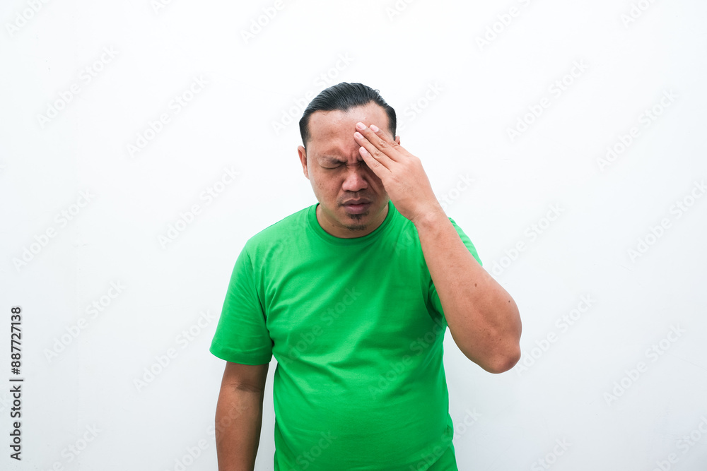 asian man wearing casual shirt standing over isolated white background with hand on head for pain in head because stress. Suffering asian man wearing casual shirt standing over isolated white background with hand on head for pain in head because stress. Suffering
