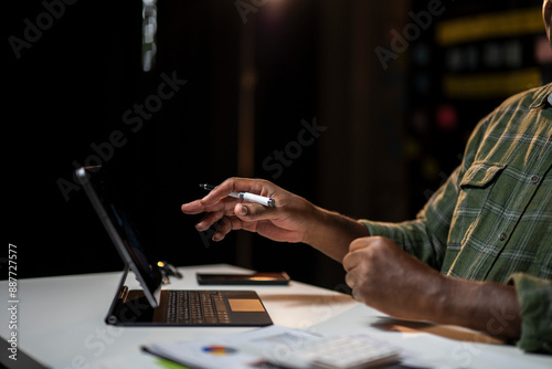 A man is using a laptop and a pen on a table