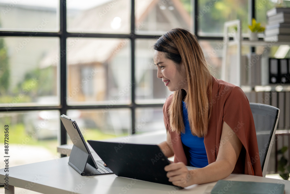 A woman is sitting at a desk with a laptop and a folder in front of her A woman is sitting at a desk with a laptop and a folder in front of her