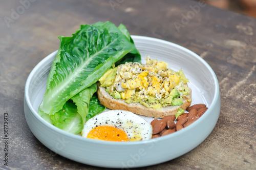 bread with egg and avocado topping with sunny side up egg , lettuce and almond photo