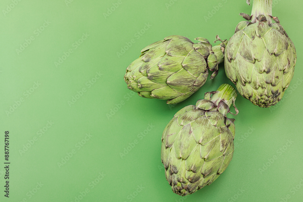 Fototapeta premium Fresh globe artichoke cooking on a green background. Traditional seasonal ingredients