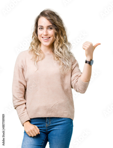 Beautiful young blonde woman wearing sweatershirt over isolated background smiling with happy face looking and pointing to the side with thumb up. photo