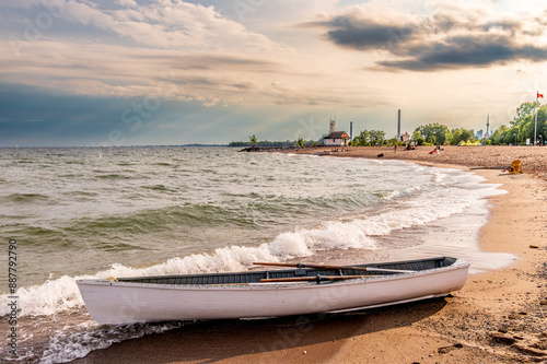 Canvas Print Beach day:  white rowboat on the sand of a public beach with people in backgroun