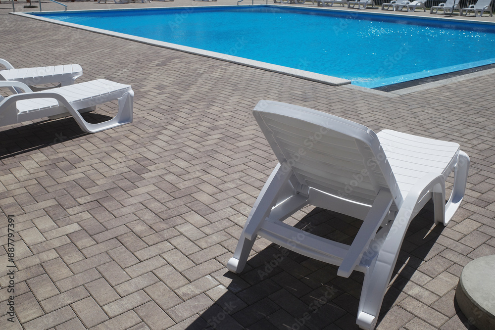 Swimming pool with blue water near the residential complex. White sun loungers, no people. Modern tourism Swimming pool with blue water near the residential complex. White sun loungers, no people. Modern tourism