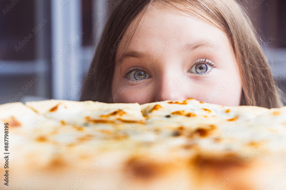 Cute girl and four cheese pizza close-up. A pre-teen girl looks into the frame as she prepares to eat pizza. Selected focus Cute girl and four cheese pizza close-up. A pre-teen girl looks into the frame as she prepares to eat pizza. Selected focus