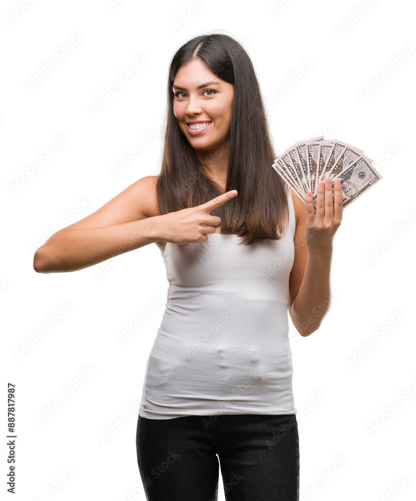 Young hispanic woman holding dollars very happy pointing with hand and finger Young hispanic woman holding dollars very happy pointing with hand and finger