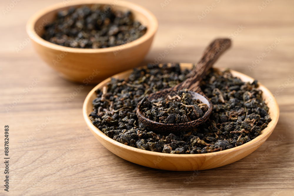 Dried Oolong tea leaves in bowl with spoon on wooden background Dried Oolong tea leaves in bowl with spoon on wooden background
