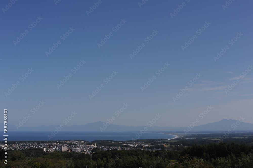 Fototapeta premium Panorama of Abashiri city with Mount Rausu and Mount Iō in the background on a sunny day with blue sky in summer, Hokkaido island, Japan