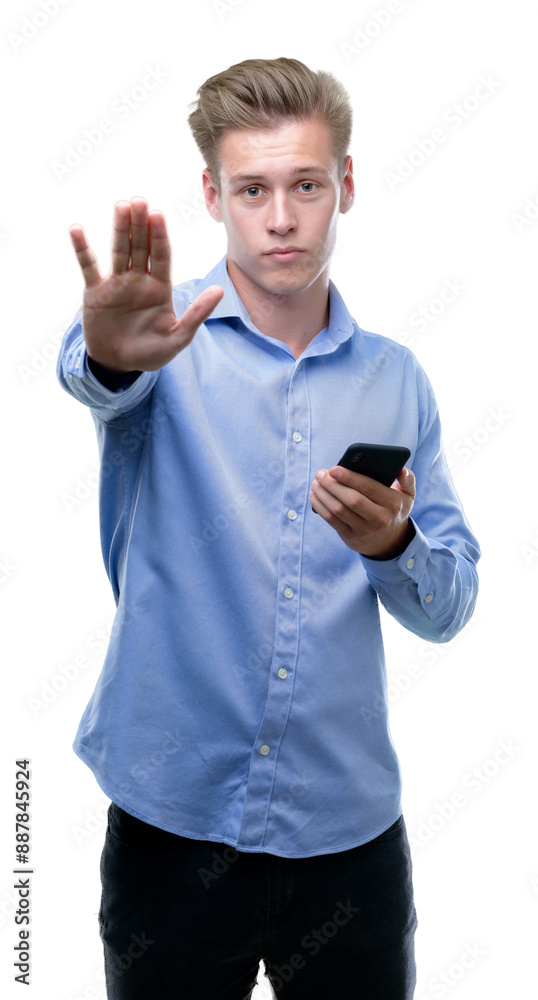 Young handsome blond man using smartphone with open hand doing stop sign with serious and confident expression, defense gesture Young handsome blond man using smartphone with open hand doing stop sign with serious and confident expression, defense gesture
