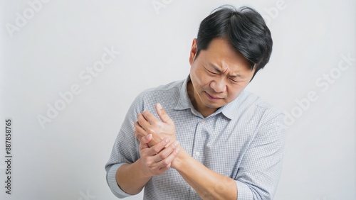 In a studio picture isolated on white, showcasing health care and medical issues, an Asian guy with sadness and wrist painâ€”possibly from carpal tunnel syndromeâ€”experiences anguish in his arms.