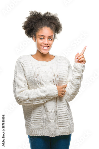 Young afro american woman wearing winter sweater over isolated background with a big smile on face, pointing with hand and finger to the side looking at the camera.