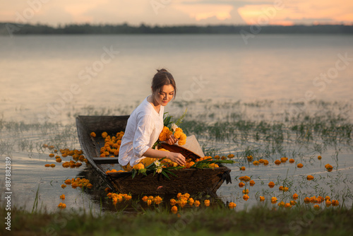 Young woman on a boat with yellow flowers in the lake during the sunset