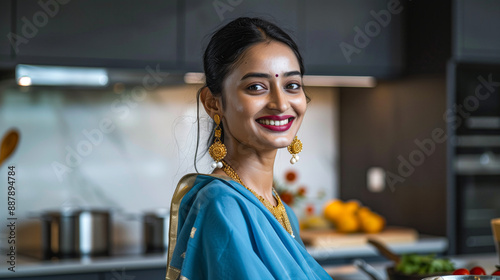 Indian modern indian woman cooking in the kitchen, wearing blue saree with smile photo