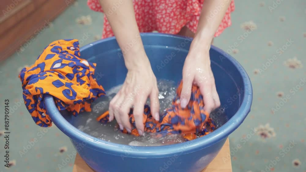 Woman washes clothes in basin with her hands. Woman washes clothes in basin with her hands.