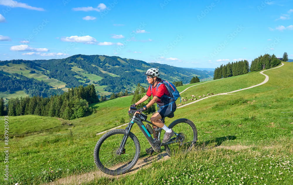 nice active senior woman riding her electric mountain bike at Mount Huendle in Oberstaufen, Allgaeu Alps , Bavaria, Germany nice active senior woman riding her electric mountain bike at Mount Huendle in Oberstaufen, Allgaeu Alps , Bavaria, Germany