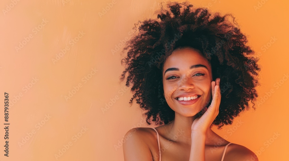 Happy young african woman with curly hair in an orange sweater, laughing with eyes closed against a matching orange background. Happy young african woman with curly hair in an orange sweater, laughing with eyes closed against a matching orange background.
