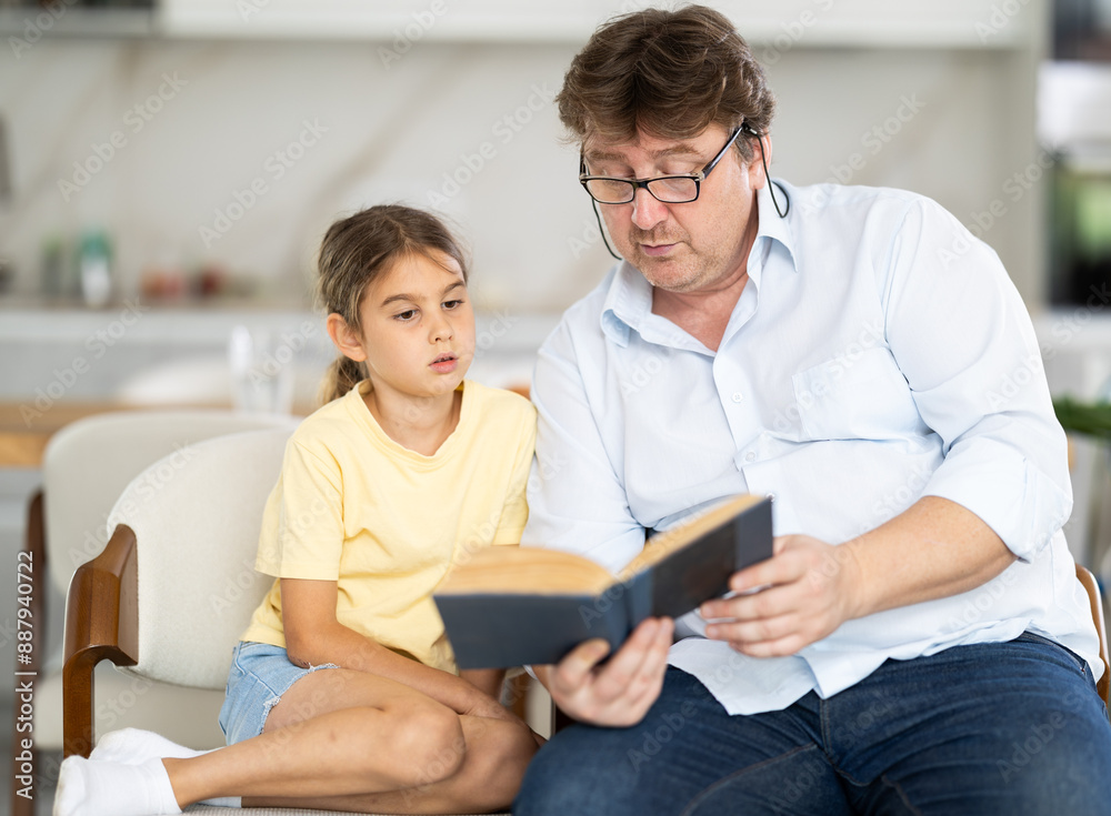 Father reading a book to his little cute daughter