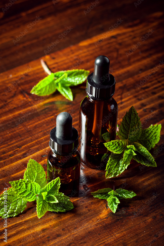 Fresh mint leaves, essential oil on wooden table
