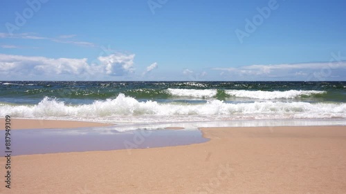 Sandy beach with gentle waves and blue sky, ocean view, coastal scenery, summer vacation, tranquil seascape, clear water