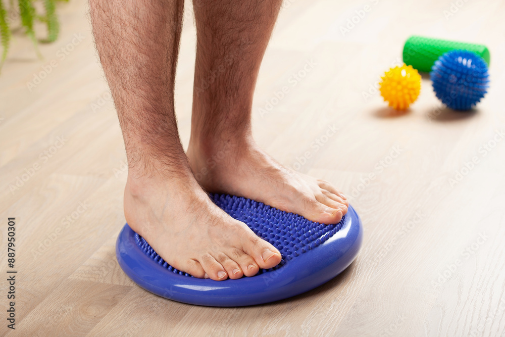 © Olga Miltsova - man doing flatfoot correction gymnastic exercise balancing on massage cushion at home
