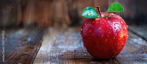 Apple with water droplets on a wooden surface creating a vibrant and fresh scene with ample copy space image
