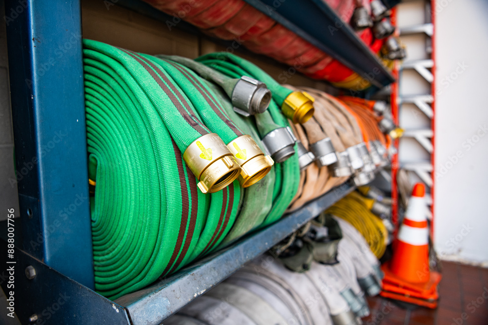 Fire hoses of different colors are stacked in rows on a fire rack.