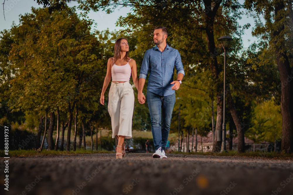 Couple Walking Hand In Hand Through A Park At Sunset Couple Walking Hand In Hand Through A Park At Sunset