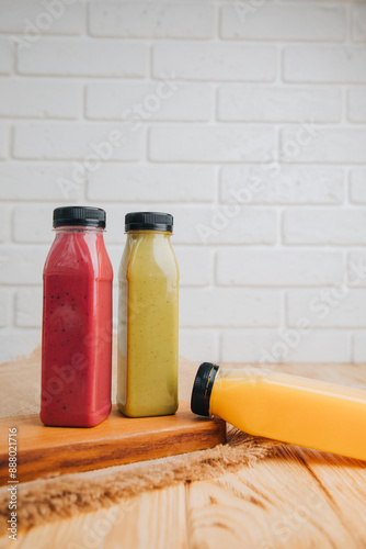 Fruit and vegetable smoothies in transparent plastic bottles. Red, green, orange smoothies on a wooden table. The concept of healthy eating. Front view