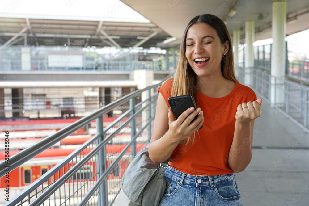 Excited Brazilian girl clenches her fist in victory holding smartphone in Sao Paulo, Brazil
