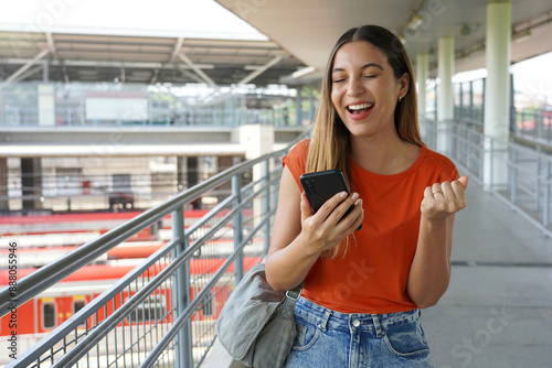 Excited Brazilian girl clenches her fist in victory holding smartphone in Sao Paulo, Brazil photo