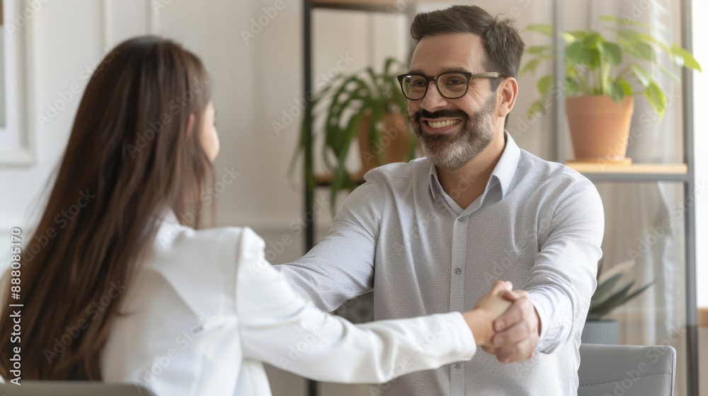 Smiling middle-aged business man shaking hands with partner while making partnership collaboration agreement. Human resources manager and new hire shaking hands during onboarding interview. Smiling middle-aged business man shaking hands with partner while making partnership collaboration agreement. Human resources manager and new hire shaking hands during onboarding interview.