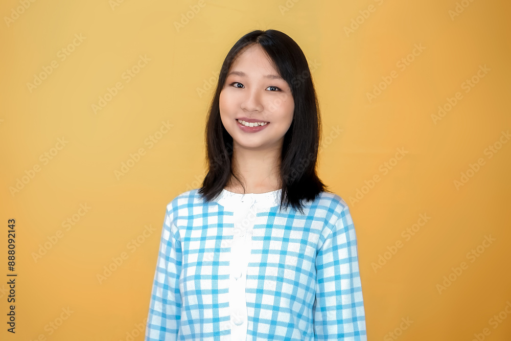 Portrait of a confident smiling girl standing with arms folded and looking at the camera isolated over yellow background Portrait of a confident smiling girl standing with arms folded and looking at the camera isolated over yellow background