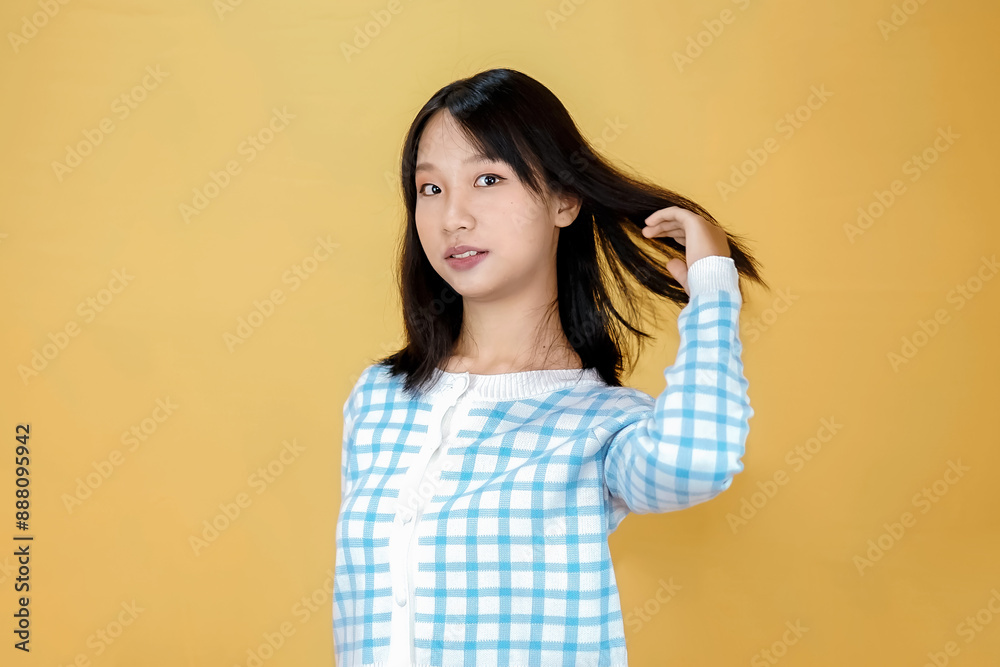 young asian woman playing or holding her hair isolated on yellow background young asian woman playing or holding her hair isolated on yellow background