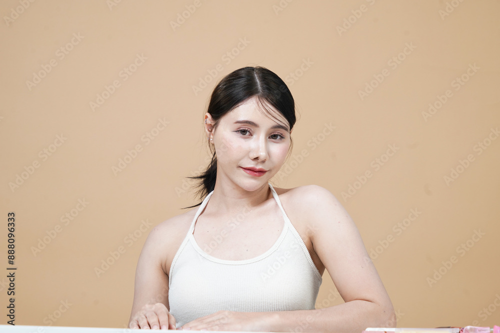Beautiful Asian woman with fair skin and Korean style makeup on brown background in studio. Beautiful Asian woman with fair skin and Korean style makeup on brown background in studio.