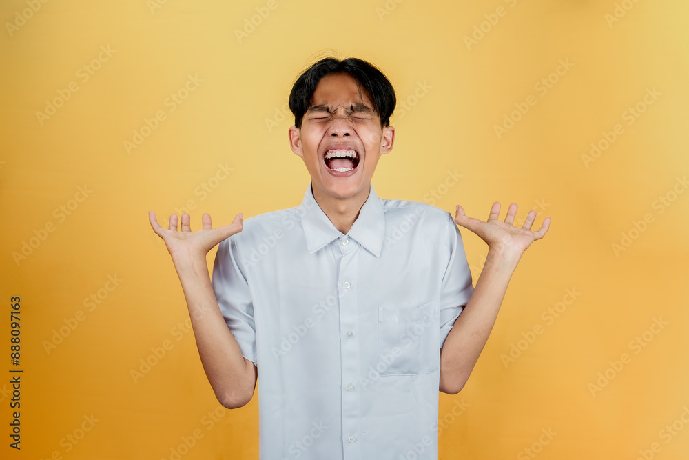 A portrait of an Asian man looks depressed isolated on yellow background. A portrait of an Asian man looks depressed isolated on yellow background.