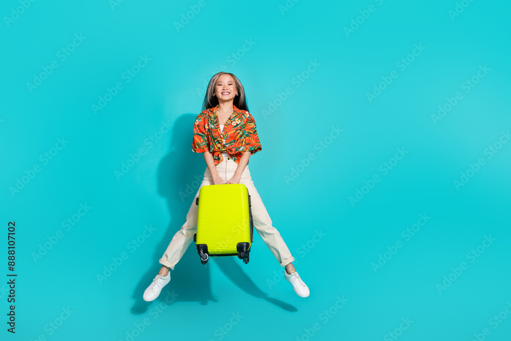 Full length photo of charming positive woman wear orange shirt holding baggage jumping high empty space isolated turquoise color background Full length photo of charming positive woman wear orange shirt holding baggage jumping high empty space isolated turquoise color background