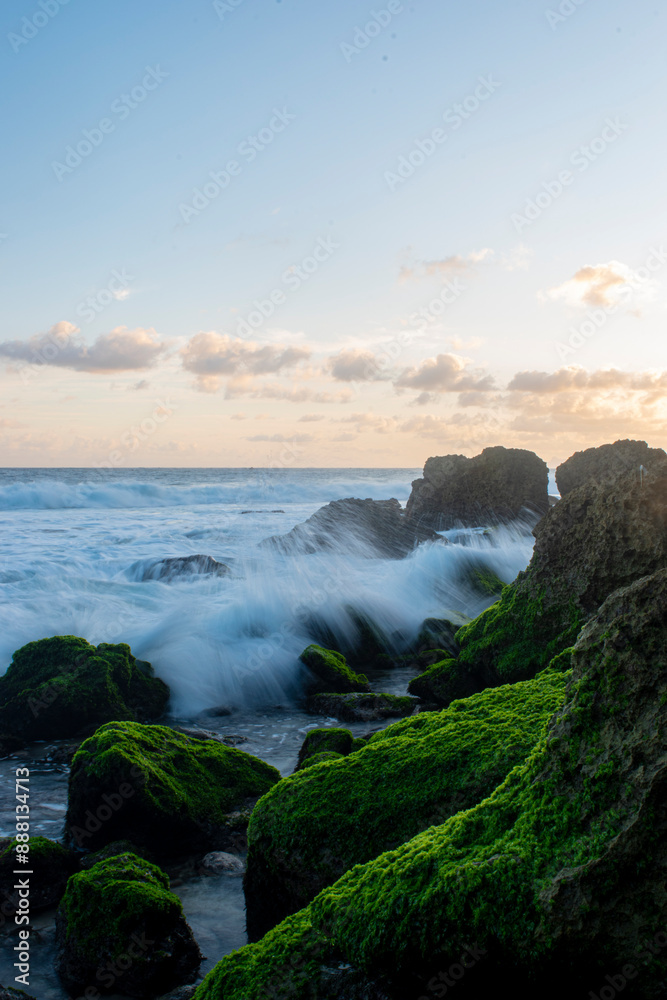 Beautiful rocky beach with green moss growing on the stones and splashing waves. Beautiful rocky beach with green moss growing on the stones and splashing waves.