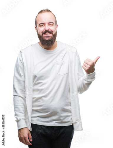 Young caucasian hipster man wearing sport clothes over isolated background smiling with happy face looking and pointing to the side with thumb up.