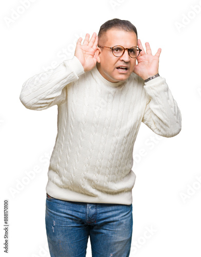 Middle age arab man wearing glasses over isolated background Trying to hear both hands on ear gesture, curious for gossip. Hearing problem, deaf