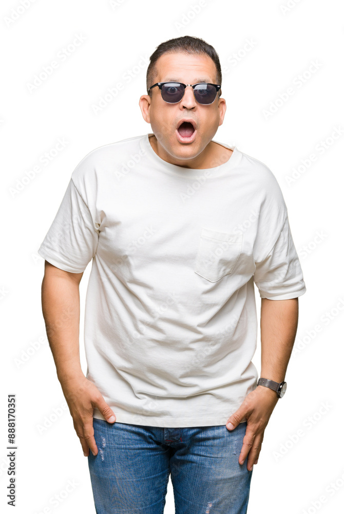 Middle age arab man wearig white t-shirt and sunglasses over isolated background afraid and shocked with surprise expression, fear and excited face. Middle age arab man wearig white t-shirt and sunglasses over isolated background afraid and shocked with surprise expression, fear and excited face.