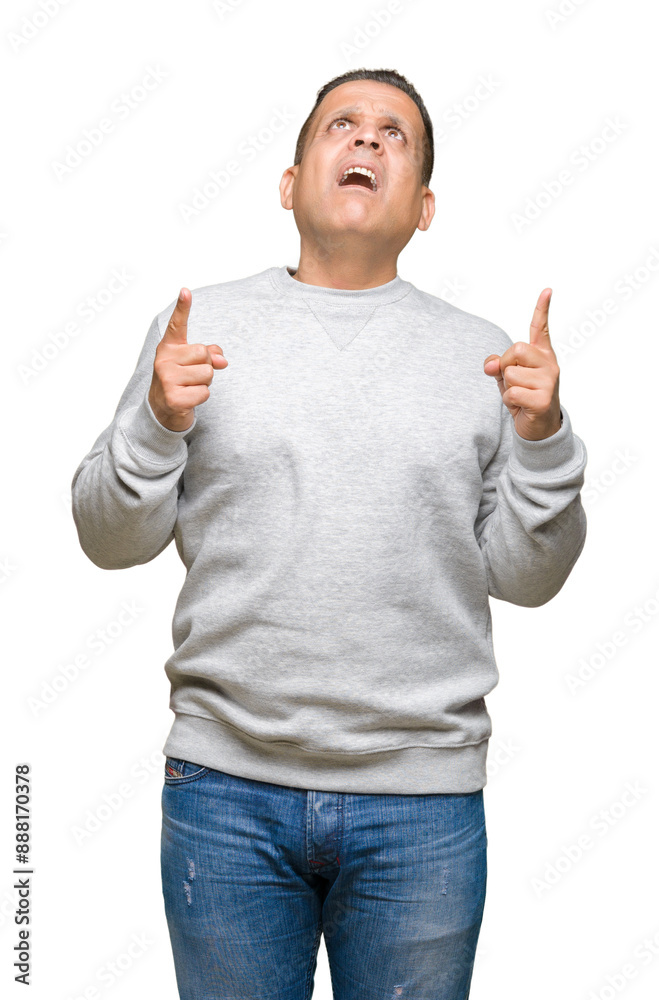 Middle age arab man wearing sport sweatshirt over isolated background amazed and surprised looking up and pointing with fingers and raised arms. Middle age arab man wearing sport sweatshirt over isolated background amazed and surprised looking up and pointing with fingers and raised arms.