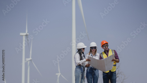 Workers talking by wind turbines in rural landscape. Technician discussing with engineers about wind turbine. Renewable energy from the wind.