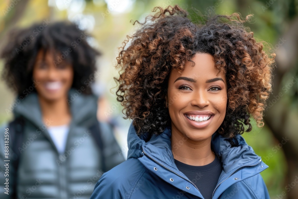 A woman with curly hair smiles brightly as she walks outdoors on a fall day A woman with curly hair smiles brightly as she walks outdoors on a fall day