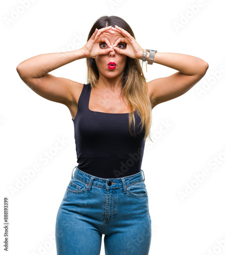 Young beautiful woman over isolated background doing ok gesture like binoculars sticking tongue out, eyes looking through fingers. Crazy expression.