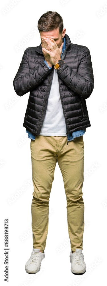 Handsome man wearing winter coat with sad expression covering face with hands while crying. Depression concept. Handsome man wearing winter coat with sad expression covering face with hands while crying. Depression concept.