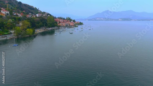 the Lake Maggiore with moored boats near the shoreline and colorful buildings in Lesa, Italy